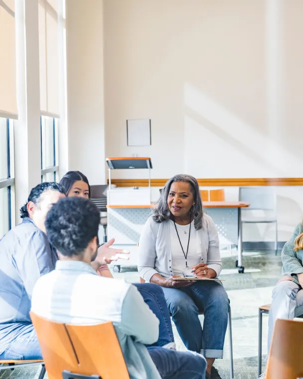 A workgroup of colleagues talk together in a bright meeting room