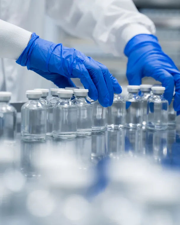 gloved hands sorting vials in a manufacturing facility