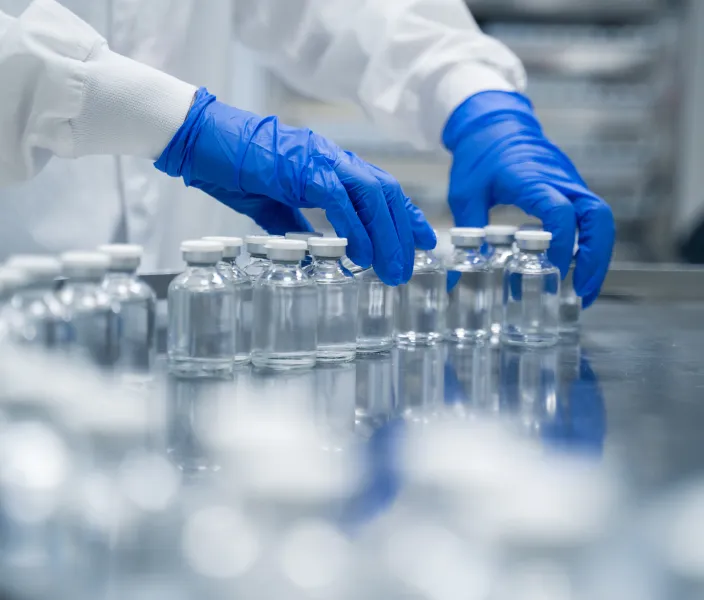 gloved hands sorting vials in a manufacturing facility