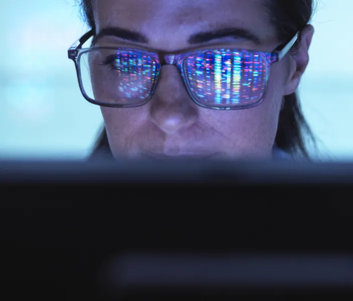 Woman looking at a computer, reflection in her glasses.