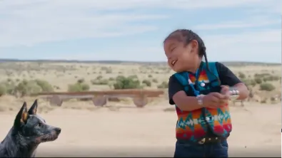 A little child plays with their dog in the desert