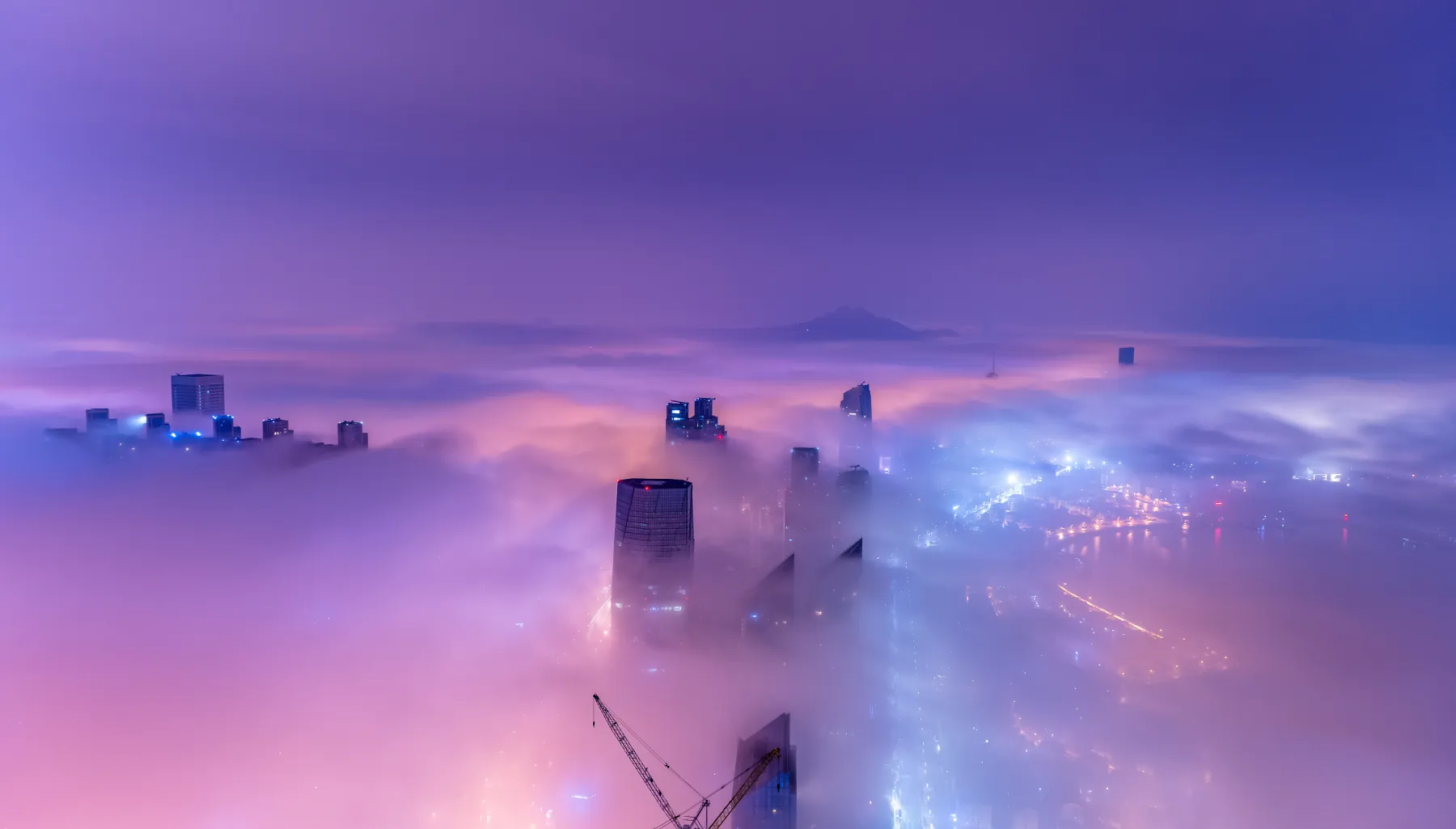 Skyline of a city at night, covered in fog