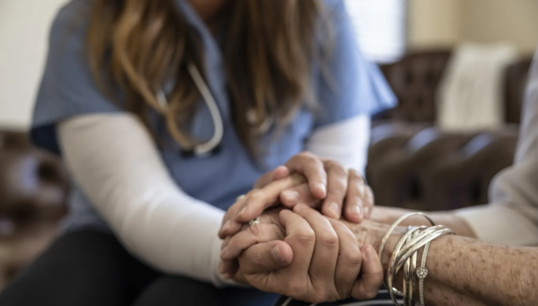 Home healthcare nurse holding hands of elderly patient