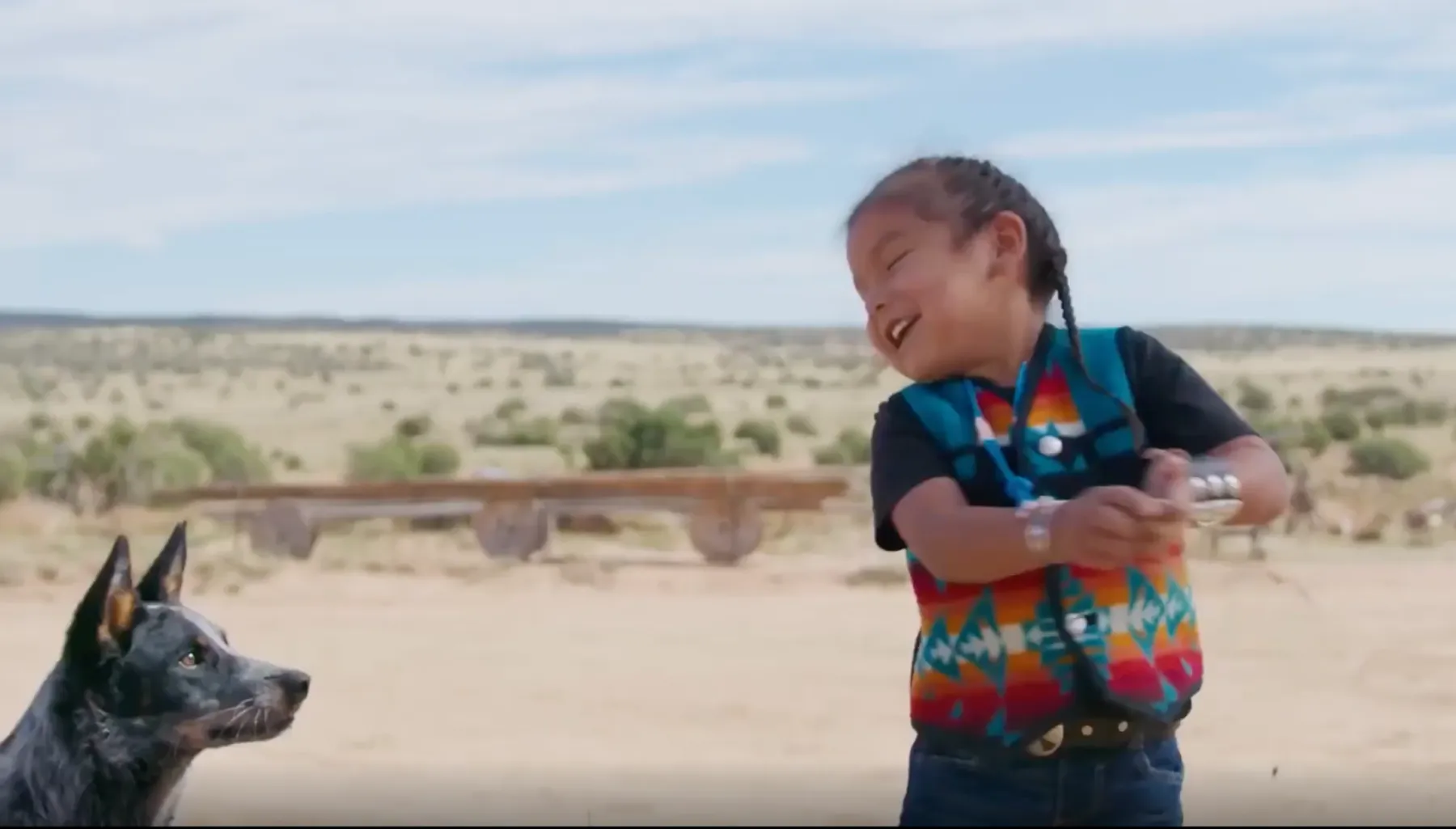 A little child plays with their dog in the desert