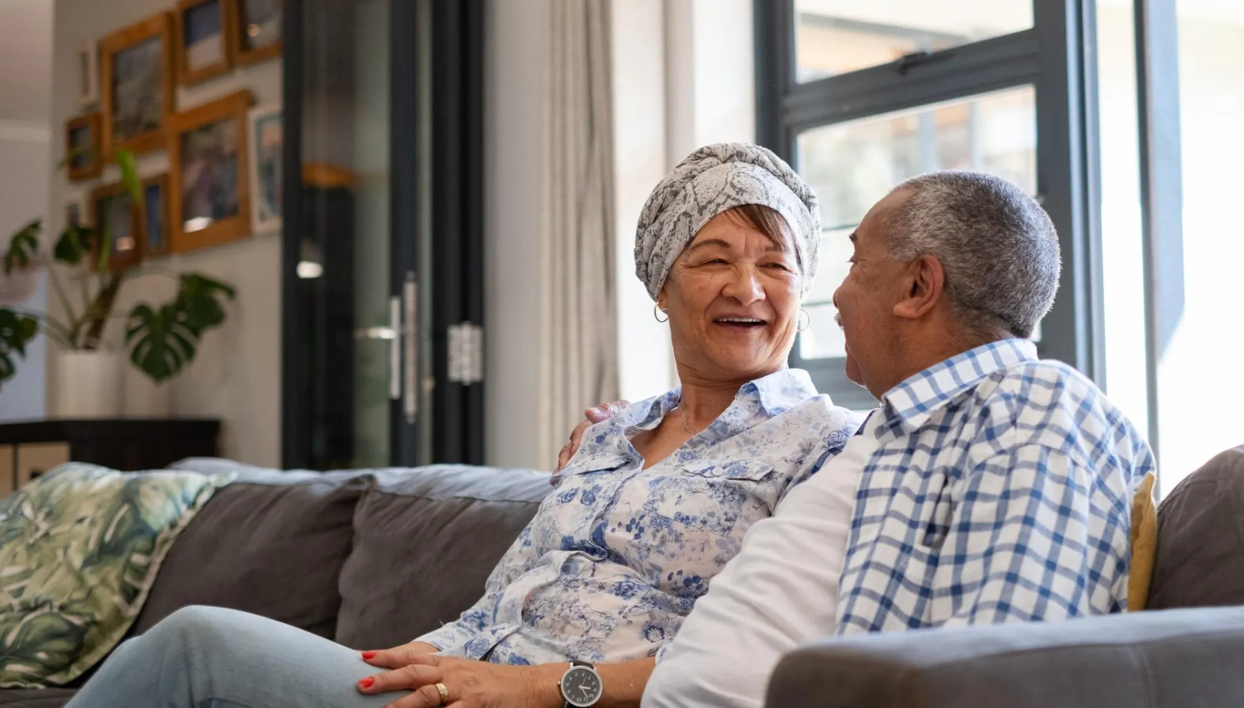 A senior couple laughs as they chat on a couch