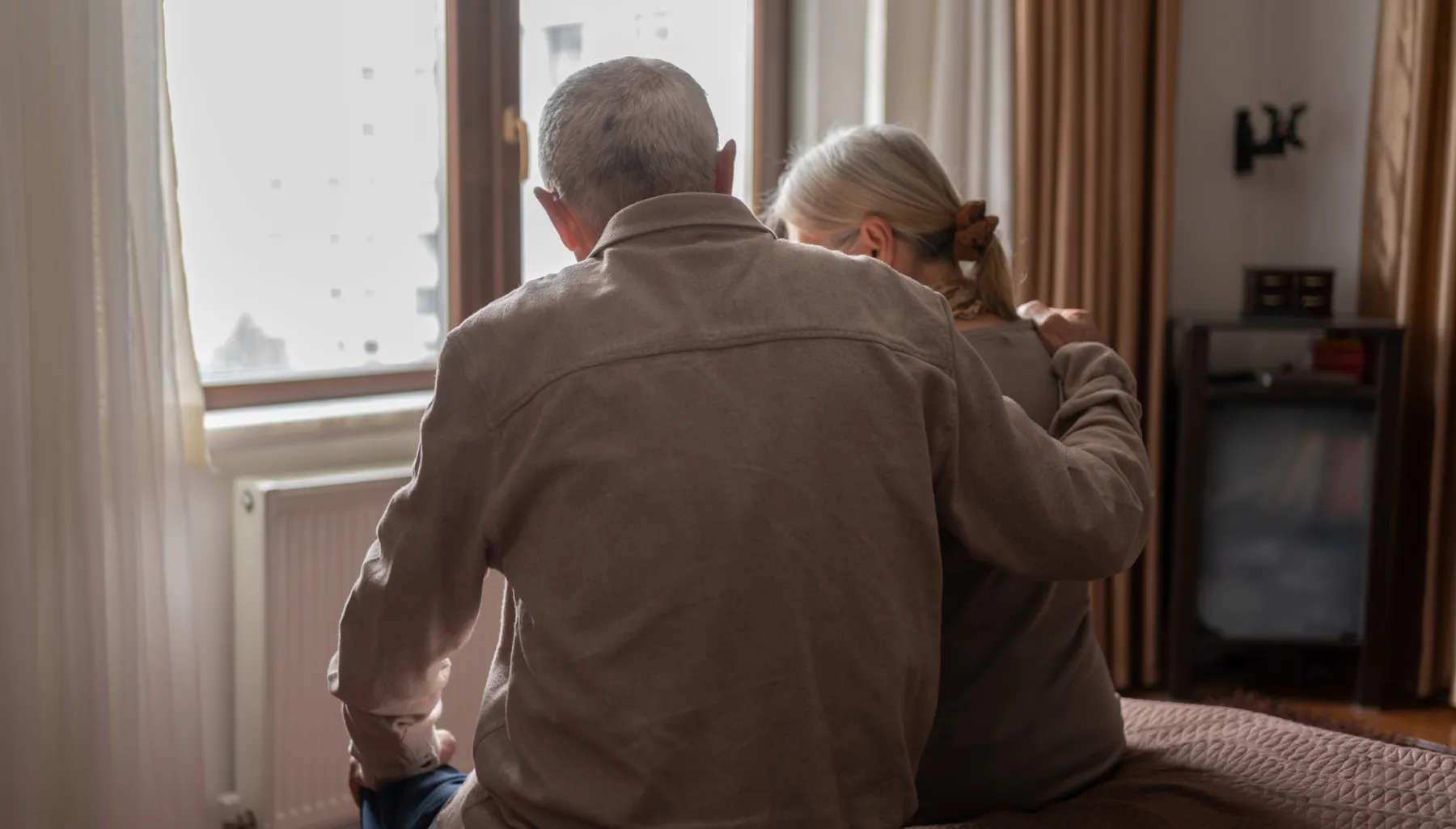 Contemplative senior couple sits on a bed