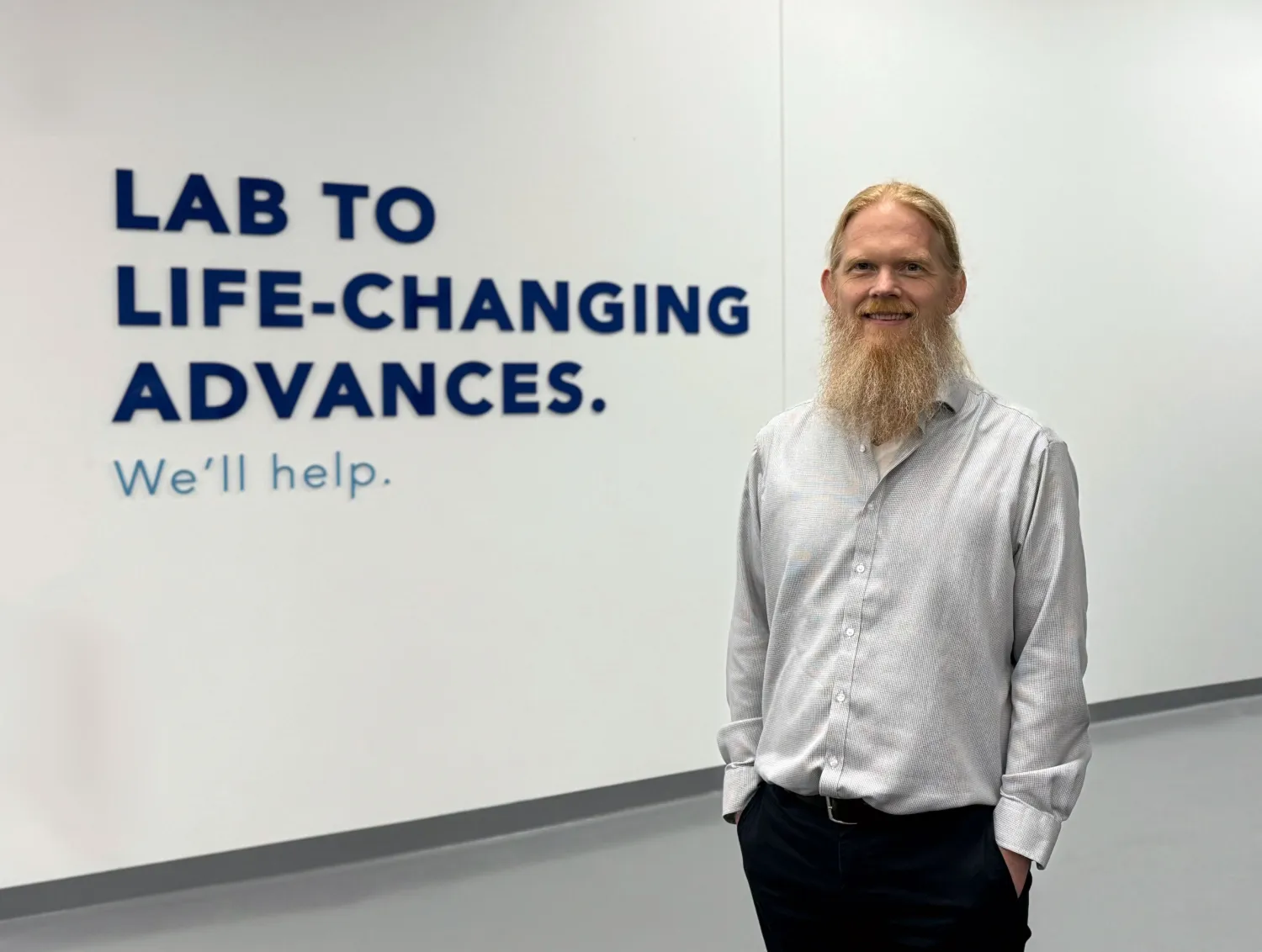 A man standing in a white hallway smiling