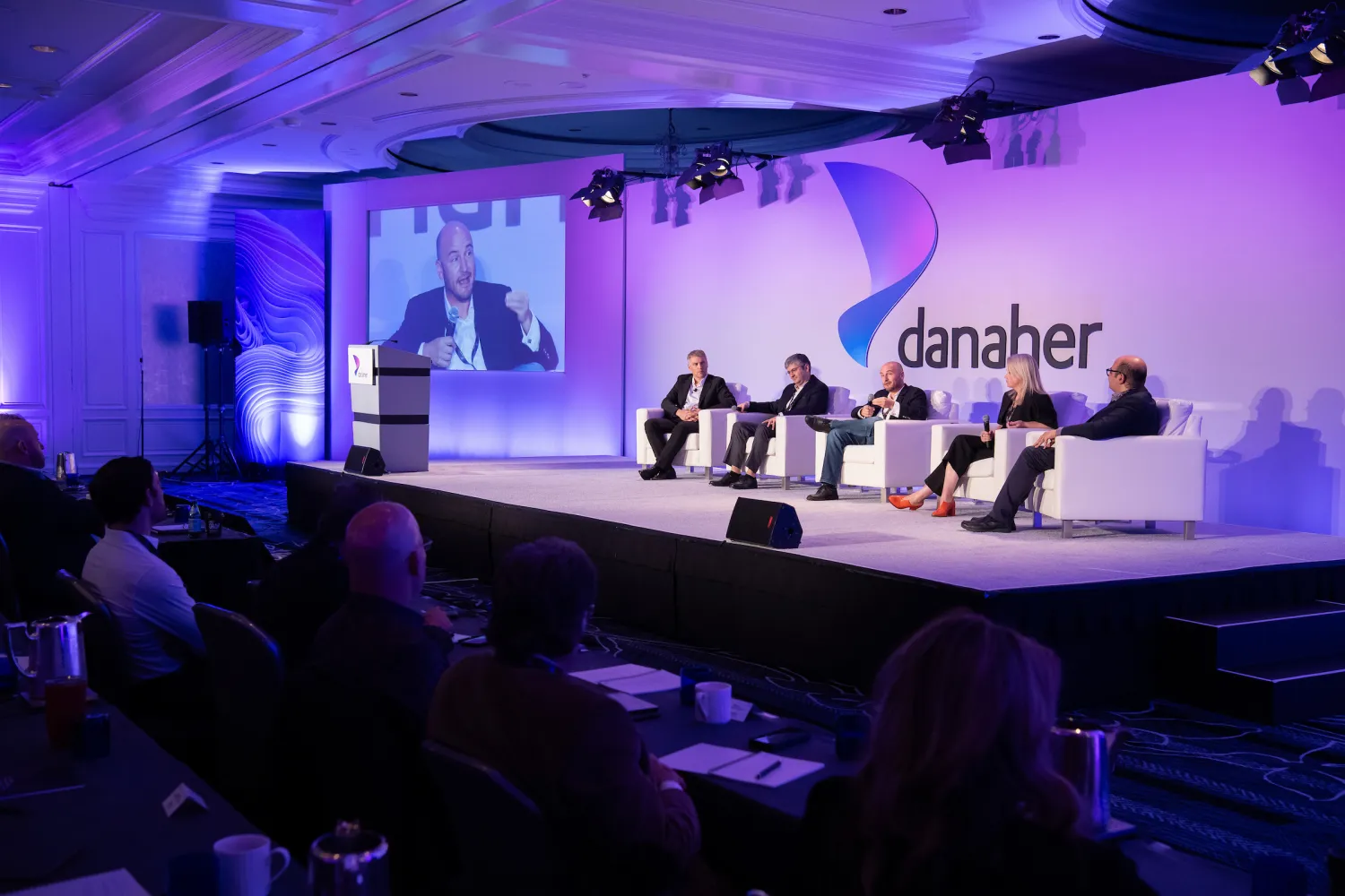 Speakers sitting on stage at the Danaher Summit
