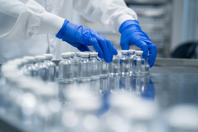 gloved hands sorting vials in a manufacturing facility